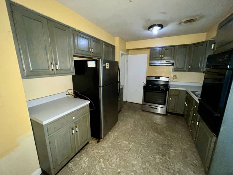 Close-up view of kitchen at 5900 Winthrope Avenue with gray wood cabinets, appliances, and vinyl flooring.