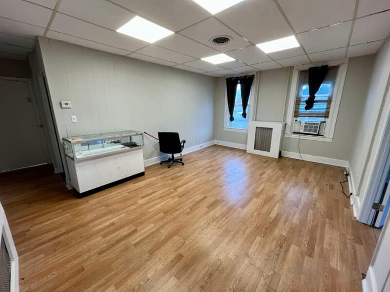 Middle first-floor unit at 5839 Belair Road with vinyl flooring, drop ceiling, and storefront display case.