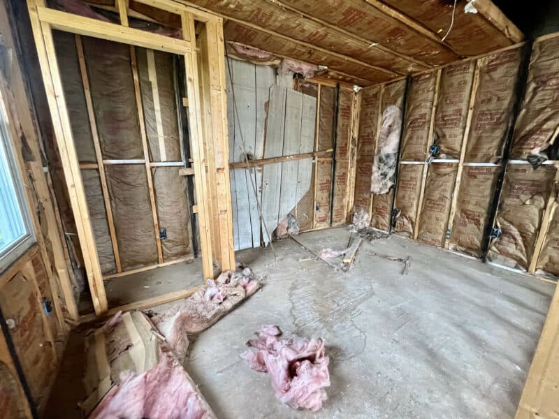 Interior view of a gutted apartment unit with exposed framing, insulation, and debris on the floor at 539-549 45th Street in Dundalk