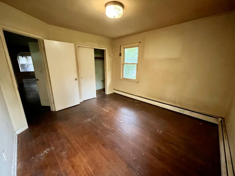 Bedroom at 5900 Winthrope Avenue with wood flooring, baseboard heating, and closet space.