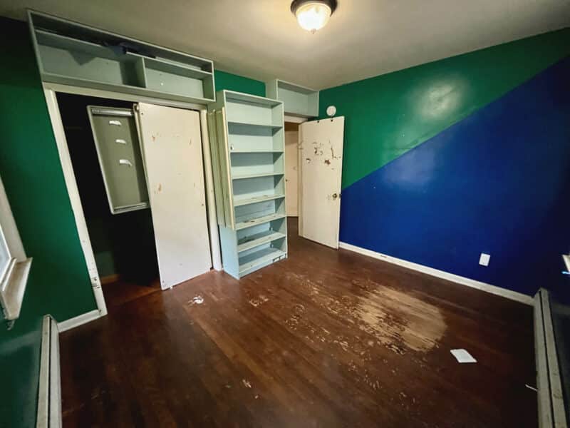 Second bedroom at 5900 Winthrope Avenue with hardwood flooring, built-in shelves, and bold green and blue accent walls.