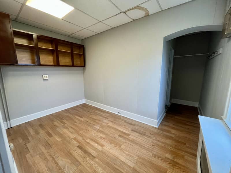 Interior room in rear first-floor unit with wood cabinetry, vinyl floors, and drop ceiling.