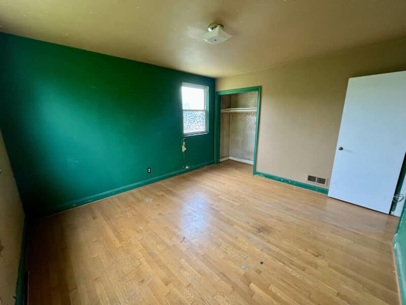 Third bedroom with green accent wall, hardwood floors, and open closet at 5501 W. Forest Park Avenue.