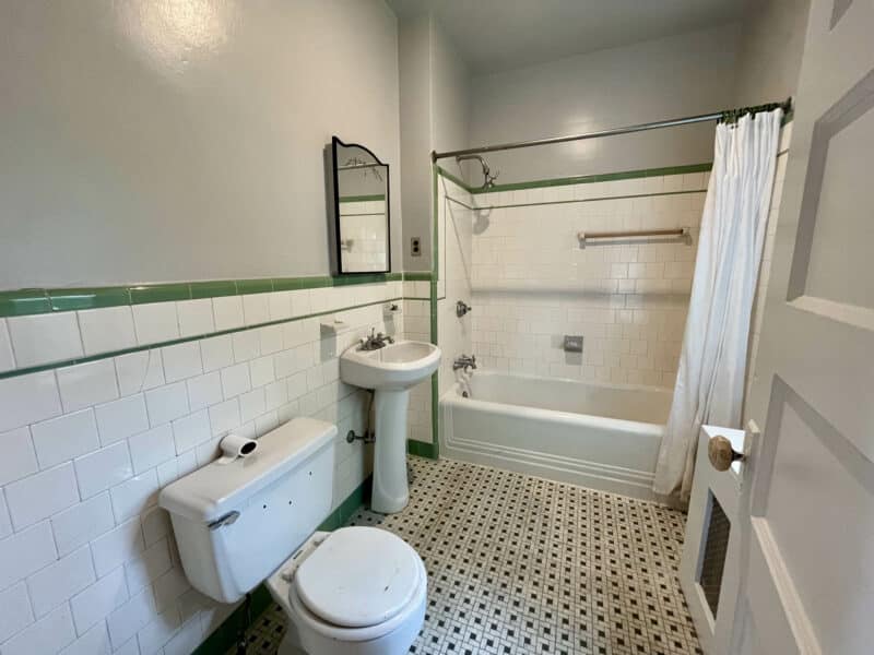 Full bathroom on first floor with pedestal sink, toilet, and tiled tub surround at 5839 Belair Road.