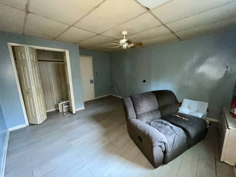 Living area of first apartment at 4831 Belair Road with vinyl floors, ceiling fan, and recliner.