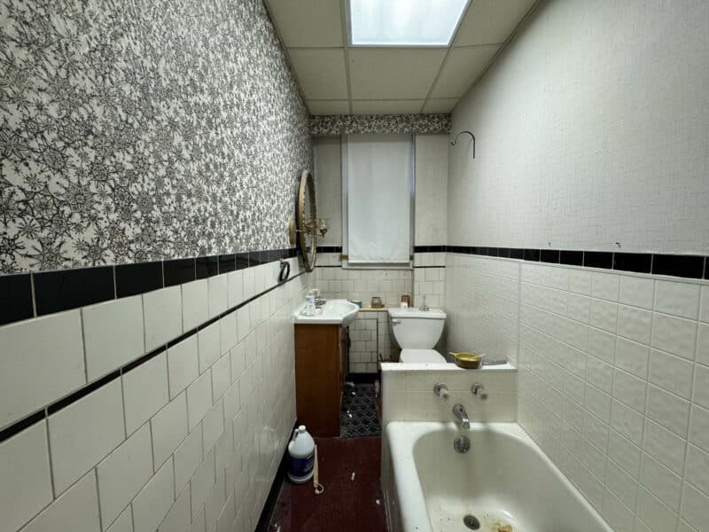 Full bathroom featuring classic white tile with black trim, a bathtub, pedestal sink, and toilet at 3412 Esther Place in Highlandtown.