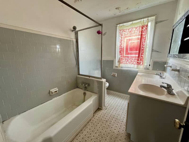 Full bathroom with vintage tile, tub/shower combo, and single vanity at 5501 W. Forest Park Avenue.