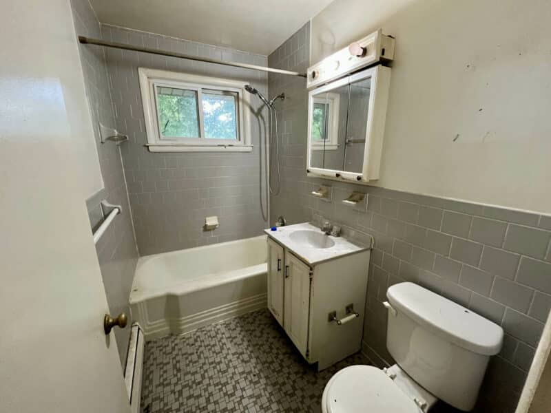 Full bathroom at 5900 Winthrope Avenue with bathtub, vanity, toilet, and gray tile walls.
