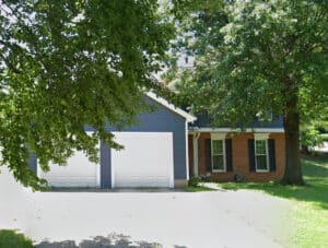 Front view of a two-story brick and siding home with attached garage and paved driveway at 1504 Pebble Beach Drive in Bowie, Maryland, listed for auction.