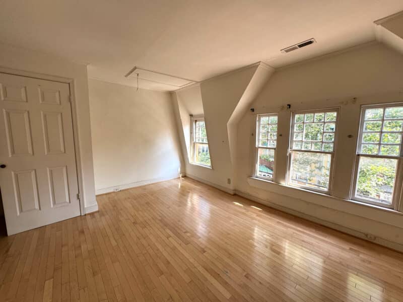 Living area with hardwood floors, angled ceiling, and multiple windows in potential ADU.