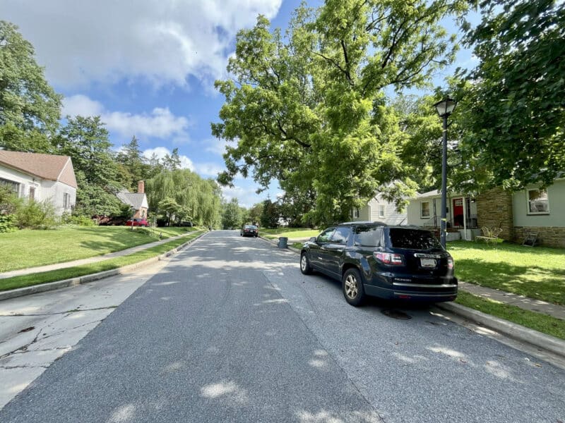 Street-level view of Dunmore Road in Catonsville, showing parked cars, mature trees, and residential homes.