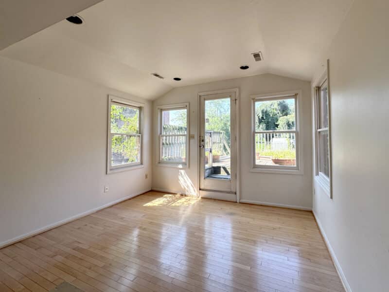 Bright bedroom with hardwood flooring and multiple windows in potential ADU.