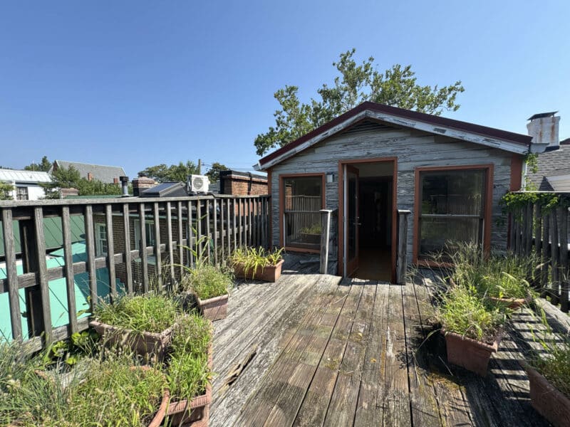 Rear sun deck on third floor with planters and wood decking.