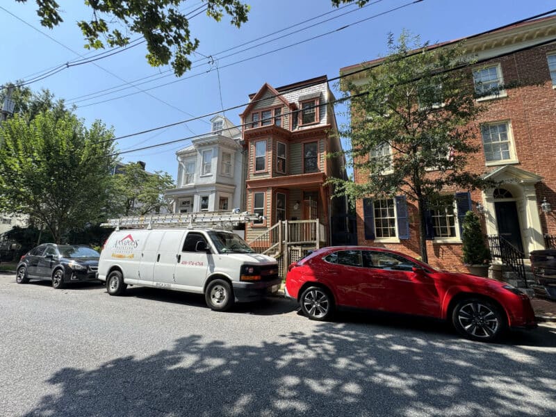 Wide-angle view of Victorian-style semi-detached townhome with covered front porch.