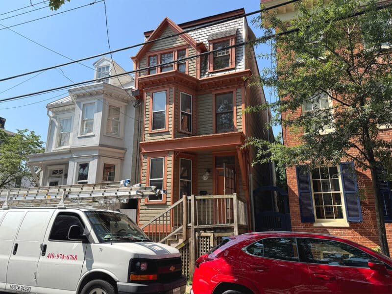 Front exterior view of a three-story Victorian townhome with bay windows and a covered porch in Downtown Annapolis.