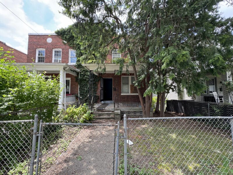 View of fenced front yard and walkway leading to the brick semi-detached home at 909 Jackson Street NE, Washington, DC.