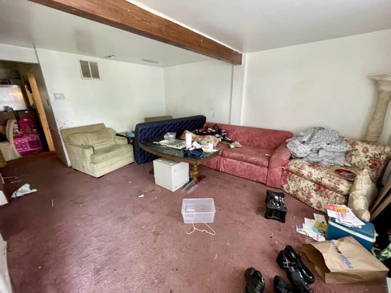 Carpeted living room with exposed beam ceiling at 12366 Bonfire Drive in Reisterstown, Maryland, shown in need of clean-out and renovation.