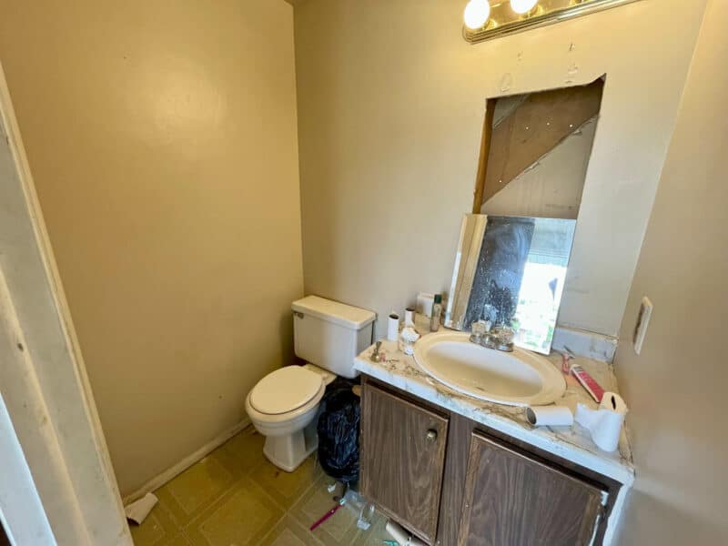 Half bathroom at 12366 Bonfire Drive in Reisterstown, featuring a toilet, single vanity, and wall-mounted mirror, in need of cosmetic renovation.