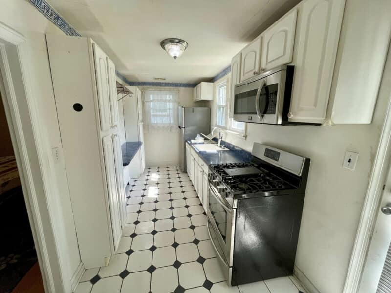 Galley-style kitchen with white cabinetry, stainless steel appliances, and ceramic tile flooring at 19 Dunmore Road.