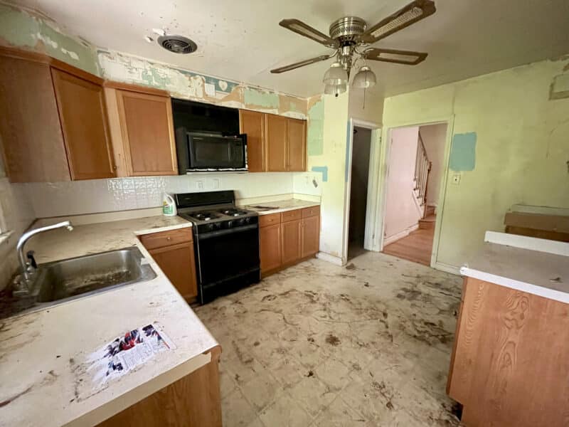 Kitchen with wood cabinets, gas stove, and ceiling fan, requiring full renovation at 1729 Edgewood Road.