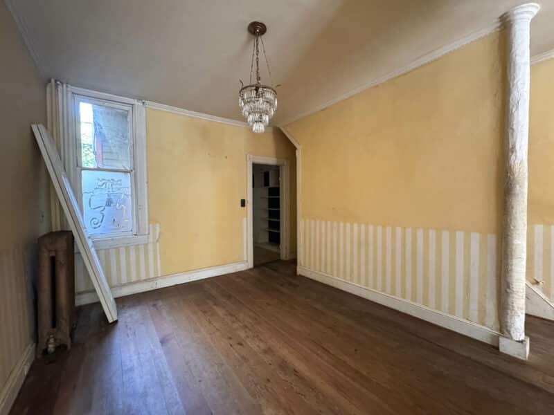 Dining room with hardwood flooring, yellow walls, vintage radiator, and decorative column at 199 Prince George Street.