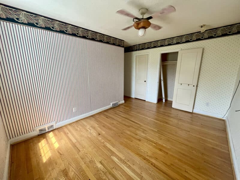 Bedroom with hardwood floors, striped wallpaper, and ceiling fan at 1729 Edgewood Road.