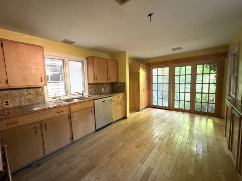 Spacious kitchen with wood floors, natural wood cabinets, granite counters, stainless appliances, and French doors leading to rear yard.