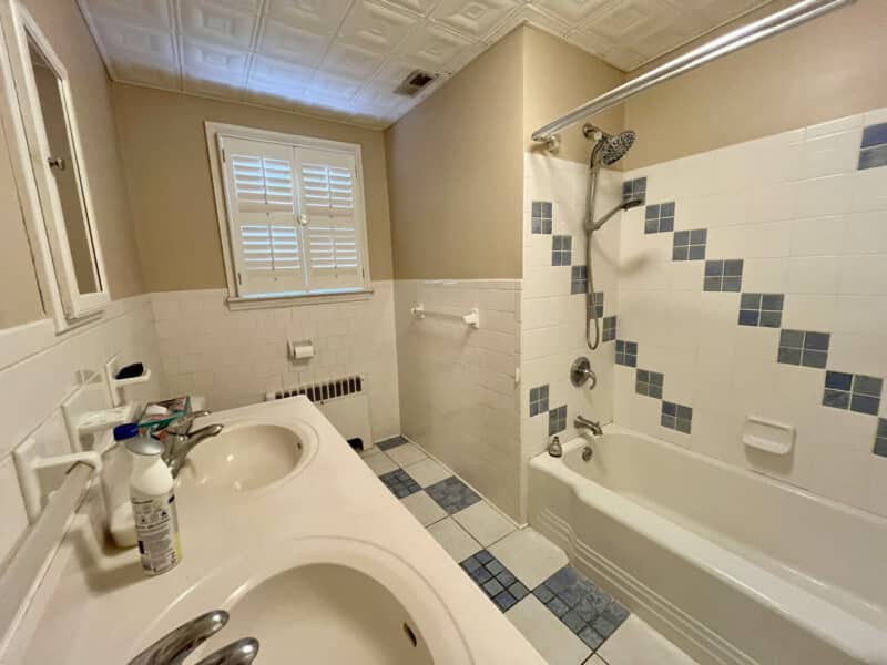 Main level full bathroom with double vanity and tiled tub-shower combo at 19 Dunmore Road.