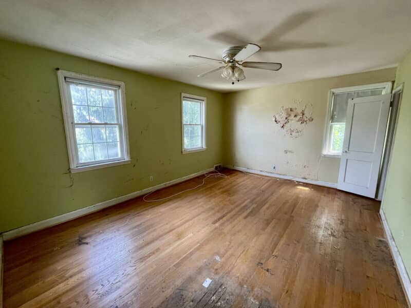 Spacious bedroom with hardwood flooring, three windows, and ceiling fan at 1729 Edgewood Road.