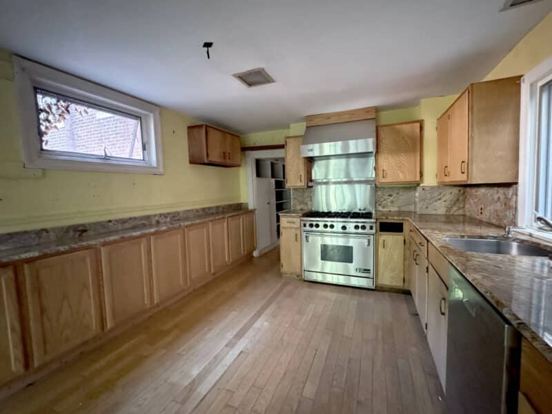 View of kitchen with Wolf stainless steel range, granite countertops, and natural wood cabinetry.