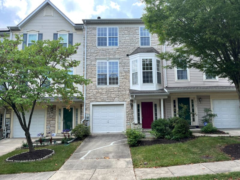 Front exterior of 8239 Brooktree Street, a three-story garage townhome with stone façade, one-car garage, and landscaped front yard in Laurel, MD.