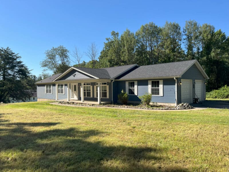 Front exterior view of a single-story ranch home with attached two-car garage and spacious front lawn.
