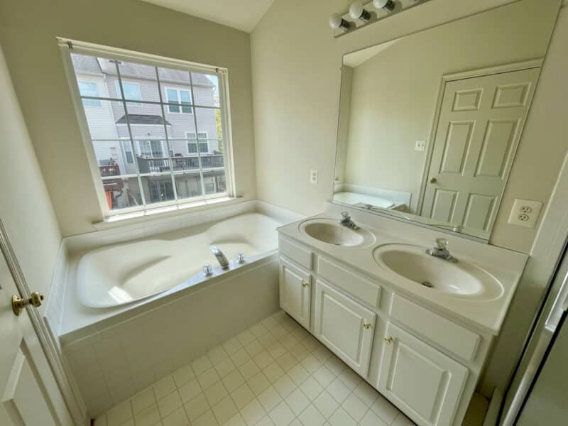 Spacious bathroom with soaking tub, dual sink vanity, and large window for natural light.