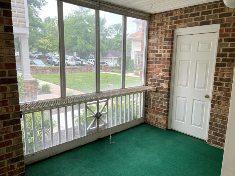 Screened-in porch with green carpet and brick walls in Bel Air condo unit.
