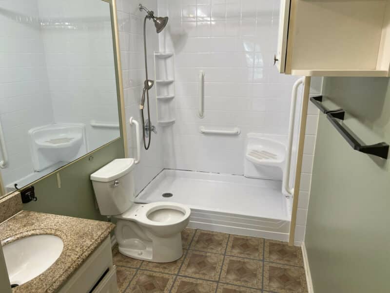 Accessible full bathroom with walk-in shower, grab bars, and tile flooring in Bel Air condominium.