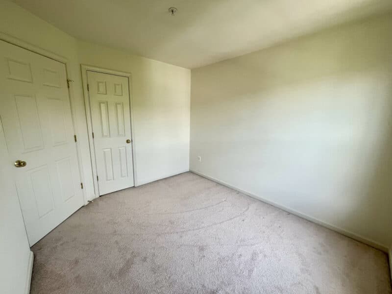 Carpeted bedroom with closet door and natural light.