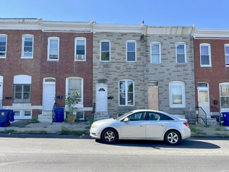 Front exterior view of 2115 E. Federal Street townhome in Broadway East, Baltimore, with parked car.