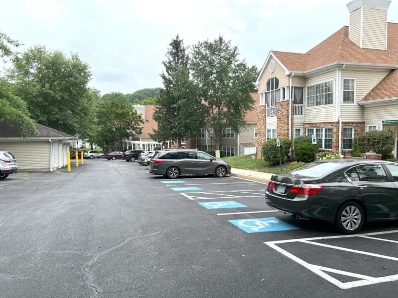 Paved parking lot with handicap spaces and exterior view of a brick and siding condominium building.