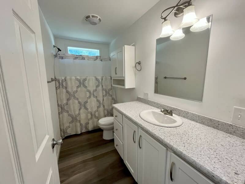 Full bathroom with extended vanity, shower-tub combination, and storage cabinets.