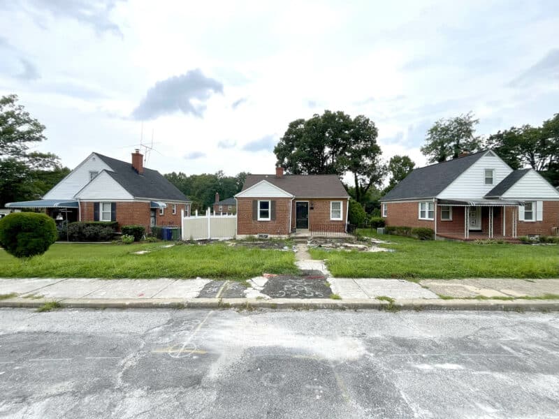 Wide-angle view of 4902 Gilray Drive and neighboring brick homes with front yards and sidewalk frontage.