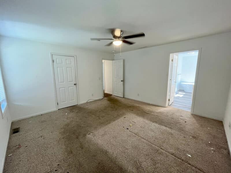 Primary bedroom with carpet, ceiling fan, and adjoining en-suite bath.