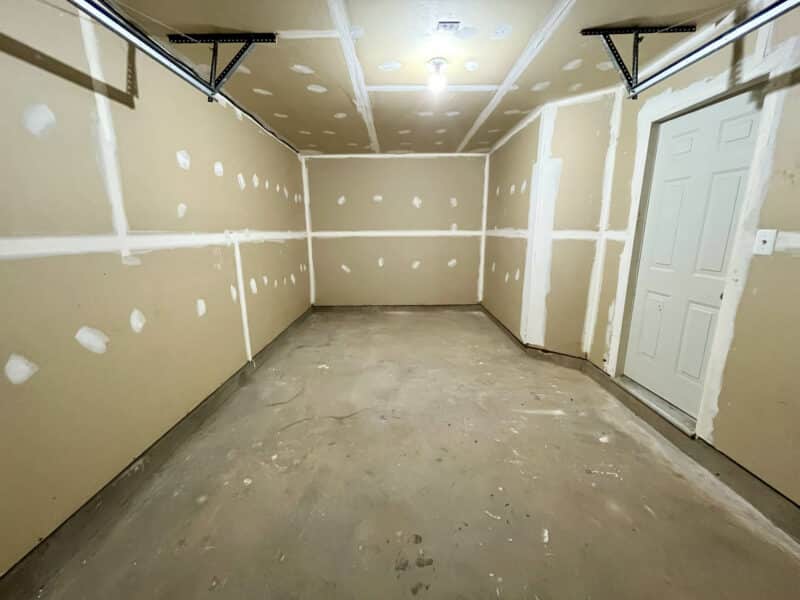 Interior of attached garage with unfinished drywall and concrete floor.