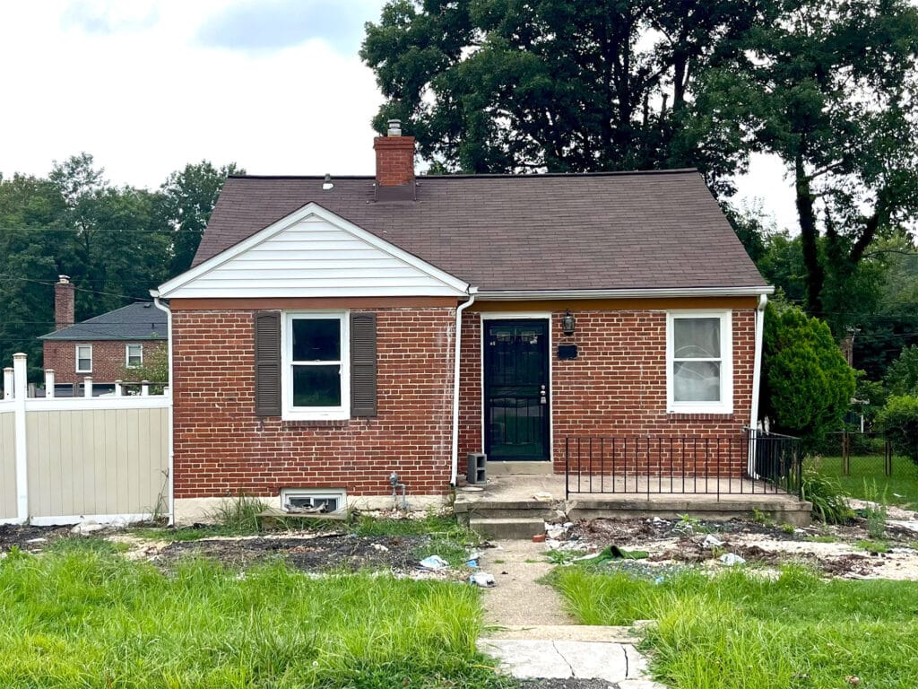 Front exterior of a brick ranch-style home with shingle roof and overgrown lawn at 4902 Gilray Drive, Baltimore.