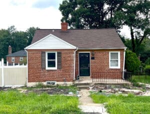 Front exterior of a brick ranch-style home with shingle roof and overgrown lawn at 4902 Gilray Drive, Baltimore.