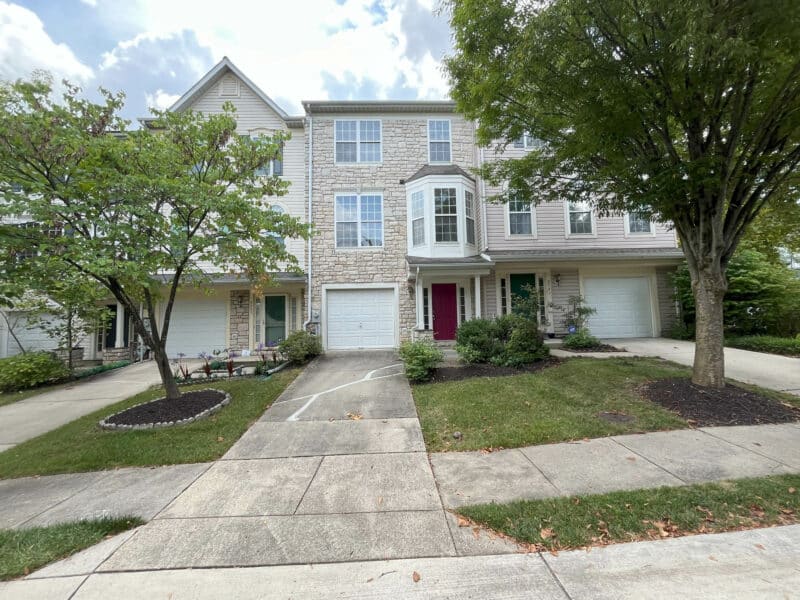 Wider view of 8239 Brooktree Street showing the townhouse and landscaped front yard with driveway, garage, and entryway.