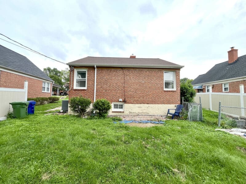 Rear exterior of brick ranch home at 4902 Gilray Drive with fenced yard and grassy open space.