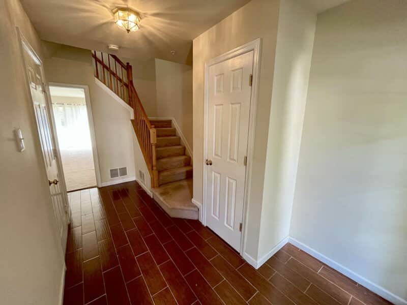 Entry foyer of townhouse with tile flooring, staircase, and double-door closet.