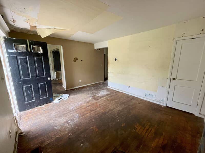 Living room at 4902 Gilray Drive with hardwood floors and visible ceiling and wall damage.