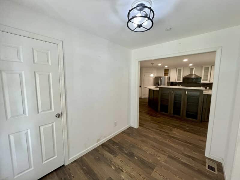 Entryway with modern light fixture and view into open-concept kitchen.