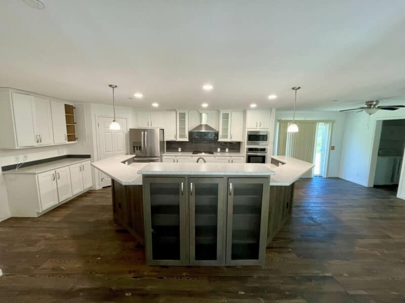 Spacious kitchen with large island, white cabinetry, and stainless steel appliances.